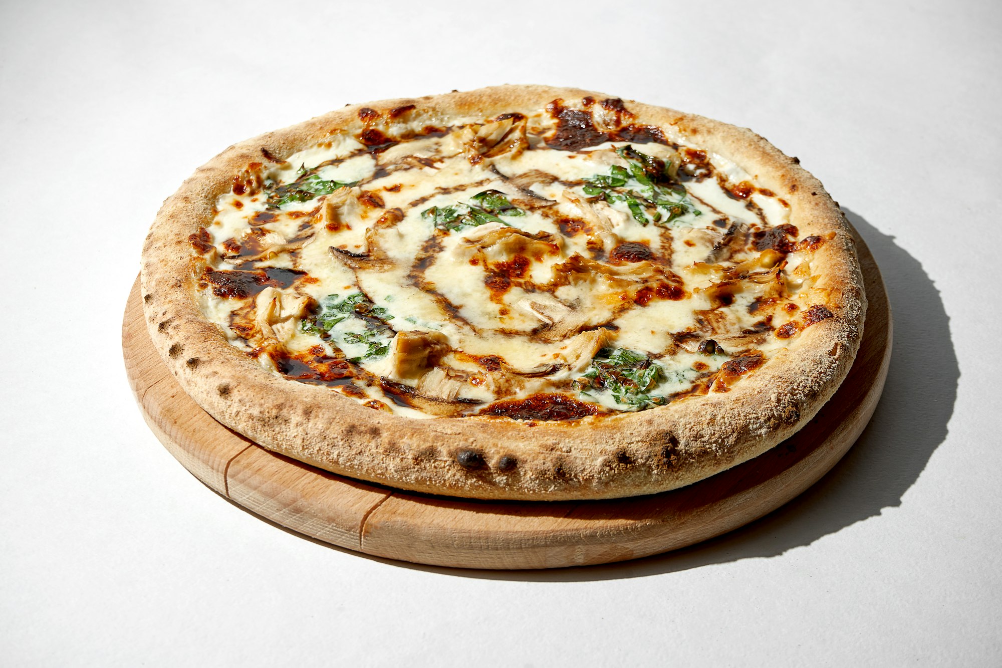 Crispy pizza with chicken and spinach and cheese sauce on a gray background.